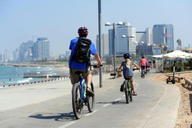 אבא וילדה רוכבים על אופניים בטיילת בתל אביב 